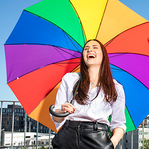 Kvinna med regnbågesparaply - en symbol för alla begrepp som ingår i paraplyet HBTQ+. Lär dig mer i artikeln hos TNG och rekrytera sedan fördomsfritt med oss!